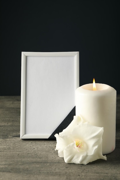 candle photo frame and flower on wooden table on black background