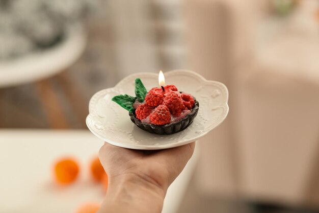 Candle soap cake in a woman's hand on the background of the kitchen