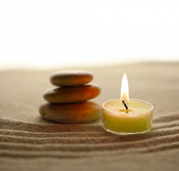 Candle and stones on sand