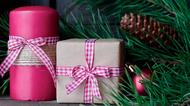 Candle on the table near the Christmas tree. Christmas present. Festive mood. Red and white candles. Christmas decoration.