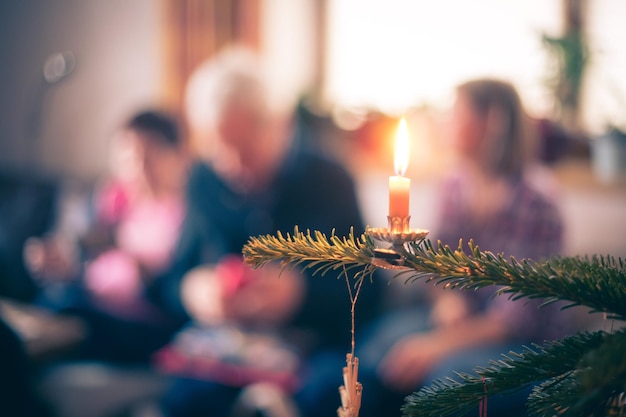 伝統的な装飾が施されたクリスマス ツリーの夜にろうそくぼやけて背景の人々