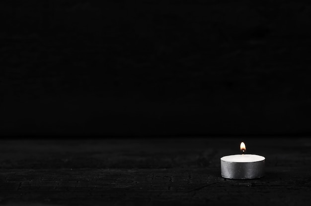 Candle with burning fire on black