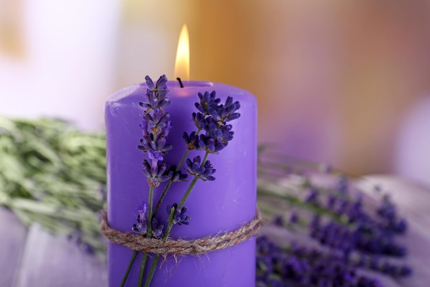 Candle with lavender flowers on bright background