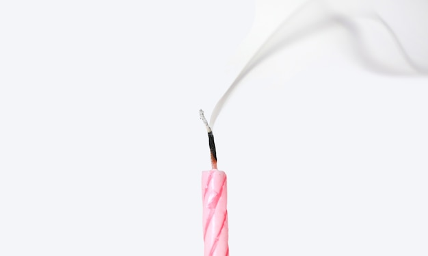 Candle with smoke blown out on white background.