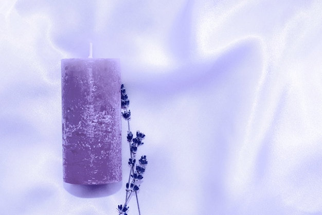 Candle with sprigs of lavender on a silk background color of the year 17-3938 Very Peri.