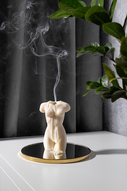 Photo candle in woman torso shape burning in grey modern interior room atmosphere and smoke after candle