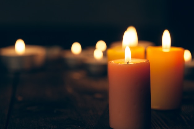 Candles burning in darkness over black background