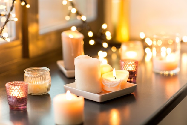 candles burning on window sill with garland lights