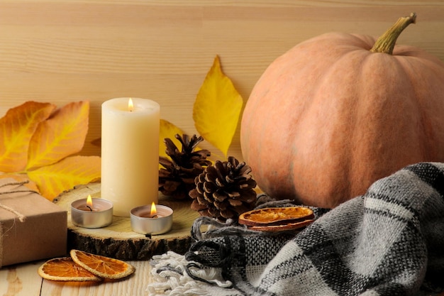 Candles cones and decorative pumpkins and autumn yellow leaves on a natural wooden table autumn composition comfort decor