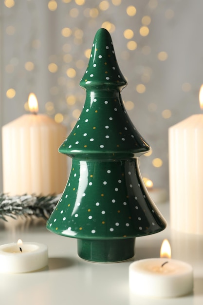 Candles and figurine of Christmas tree on gray background