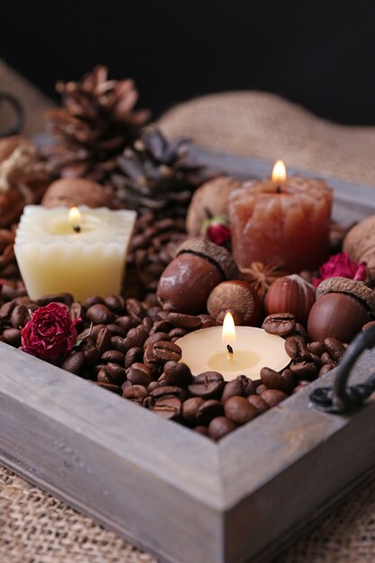 Candles on vintage tray with coffee grains and spices bumps on sackcloth background