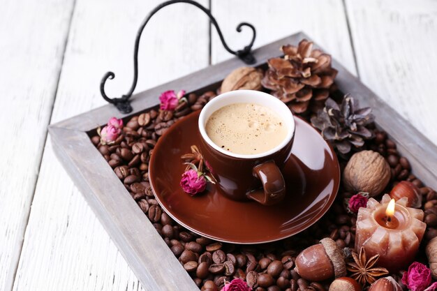 Candles on vintage tray with coffee grains and spices, cup of tea