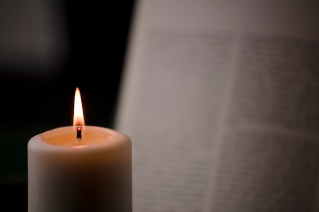 candles with flame and reading book on desk black background