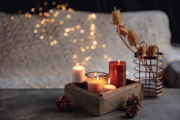Candles in the wooden box isolated on grey white background. Garland lights. The concept of home atmosphere and comfort, holidays, romantic date, winter, home comfort, indoors, Christmas or New Year.