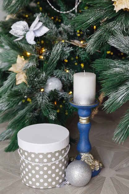 Candlestick with candle and gift box under Christmas tree