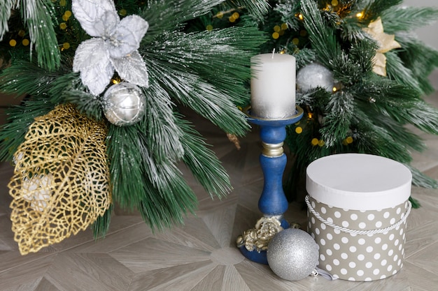 Candlestick with candle and gift box under Christmas tree