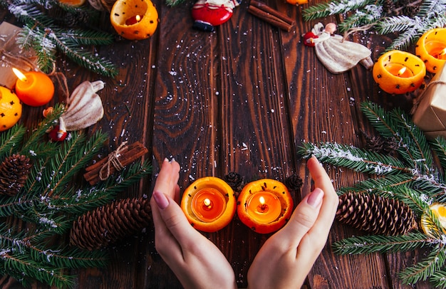 Candlesticks made of mandarins with fir branches, toys and presents on wooden table. 