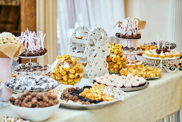 カップケーキや他のデザートスキャンディーとおいしい甘いビュッフェで飾られたキャンディーバーお誕生日おめでとうコンセプト