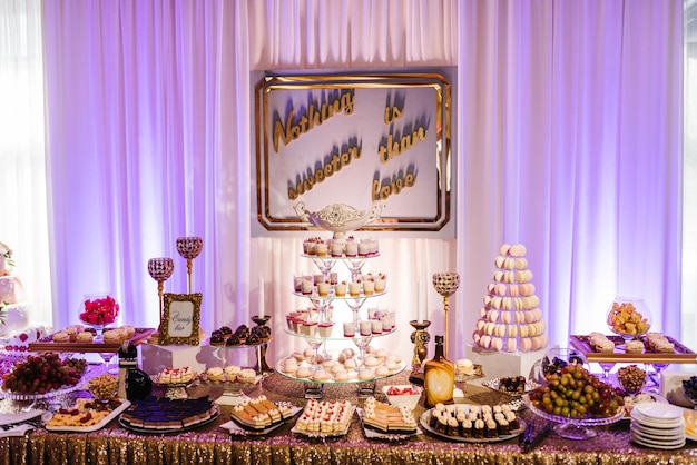 Candy bar Wedding cake decorated by candles standing of festive table with desserts