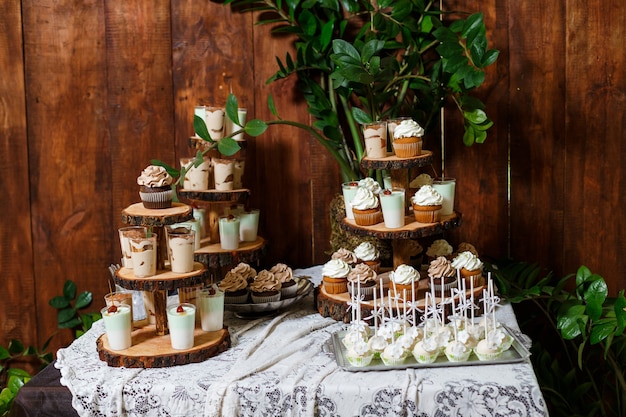 Candy bar on wooden wedding party with a lot of different candies cupcakes souffle and cakes