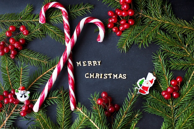 木の枝と黒の背景をキャンディします。碑文メリークリスマス