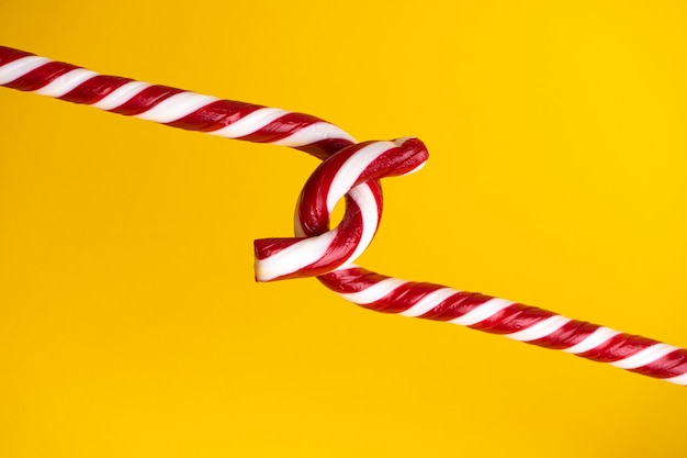 Candy cane lollipops on a yellow background, Christmas sweets.