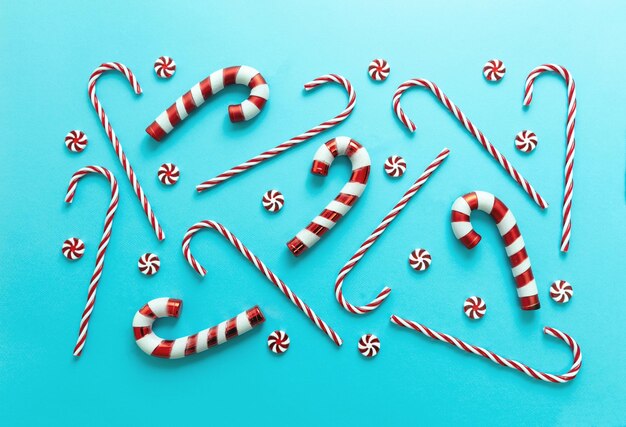 Candy canes on blue background Christmas traditional red white striped candies flat lay pattern