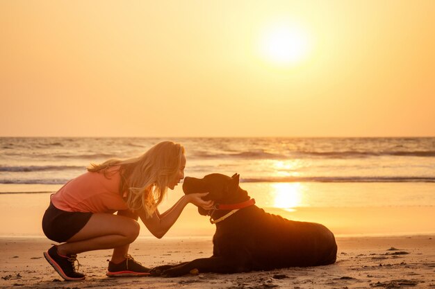 サンセットの海のビーチでカネコルソとトレーナー犬チューおもちゃ