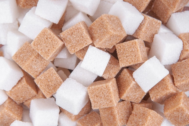 Cane sugar and white sugar cubes background top view texture