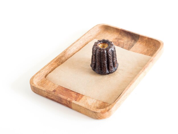 Canele op een houten server geïsoleerd op een witte achtergrond