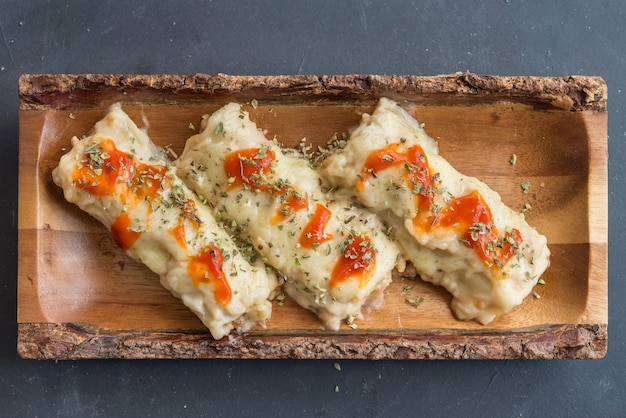 Canelones (cannelloni) met vlees gevulde pasta en kaas en tomaat op een bord