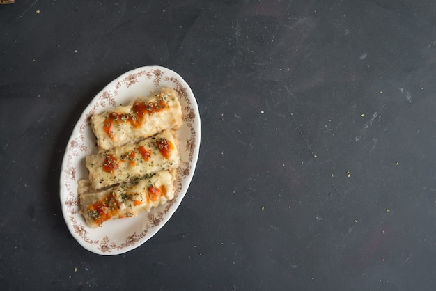 Canelones (cannelloni) met vlees gevulde pasta en kaas en tomaat op een plaatachtergrond