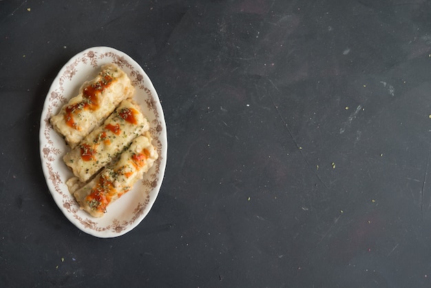 Canelones (cannelloni) with meat filled pasta and cheese and tomato on a plate