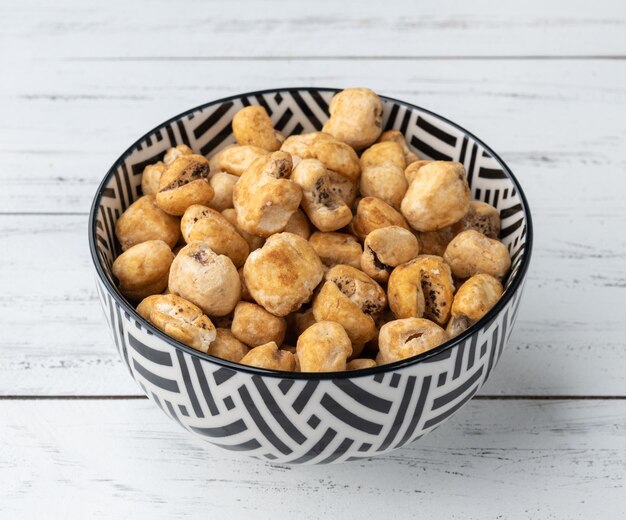 Canjica, hominy or white corn popcorn, sweet popcorn in a bowl over wooden table.