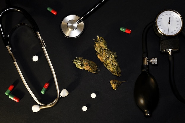 Photo cannabis on a black background nearby is a device for measuring cardiovascular pressure tonometer
