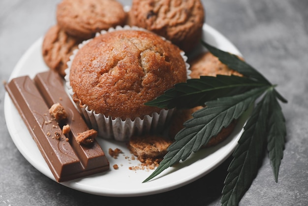 Biscotti alimentari alla cannabis con torta al cioccolato foglia di cannabis erba di marijuana su sfondo di legno e scuro delizioso dolce da dessert biscotto con pianta di foglie di canapa thc cbd erbe spuntino alimentare e medico