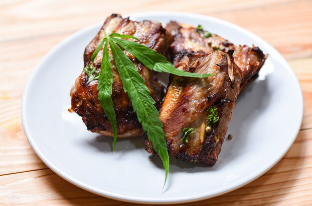 Cannabis food with bbq pork ribs grilled with herbs spices served on white plate 