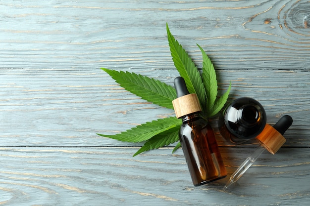 Cannabis leaf and oil on gray wooden background