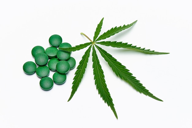 Cannabis leaf and pills on a white space.