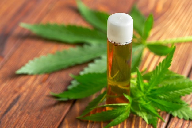 Cannabis leaves and oil on wooden background