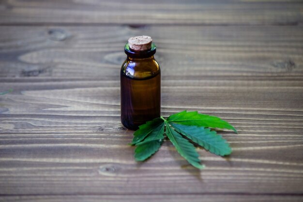 Cannabis leaves on wood background with bottles, cannabis oil. Selective focus