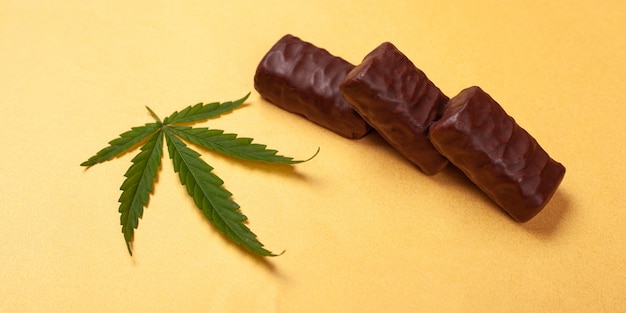 Cannabis sweets. chocolate candies with a leaf of marijuana on a yellow background.