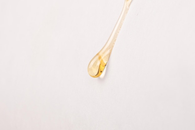 Cannabis wax resin golden drop down on white paper closeup