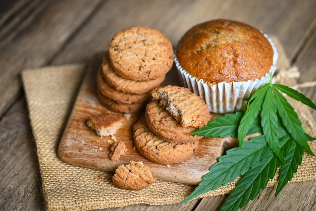 Cannabisvoedselkoekjes met cake chocolade cannabisblad marihuanakruid op houten en donkere achtergrond, heerlijk zoet dessertkoekje met hennepbladplant THC CBD kruiden voedselsnack en medisch