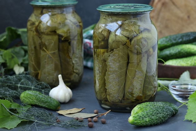 Cetrioli in scatola in foglie di vite in barattoli su uno sfondo scuro