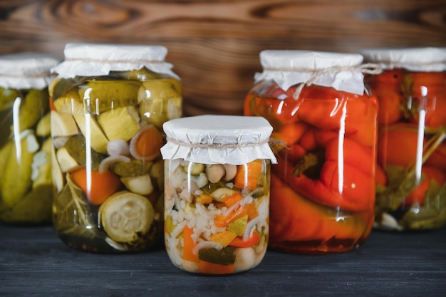 Canned cucumbers and tomatoes with craft lids on a wooden background Cucumbers and tomatoes with place for text Stocks of canned food Harvest stocks for the winter