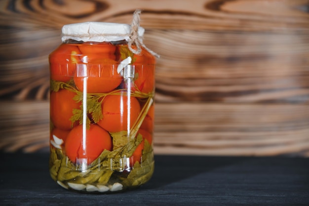 Canned cucumbers and tomatoes with craft lids on a wooden background Cucumbers and tomatoes with place for text Stocks of canned food Harvest stocks for the winter
