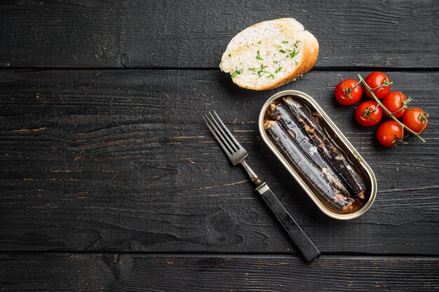 Canned fish in oil set, on black wooden table background, top view flat lay, with copy space for text