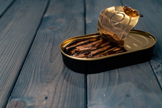 Canned fish in sauce conserve on dark wooden table