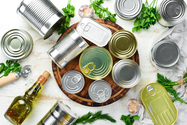 Canned food in tin jars on white wooden background Top view